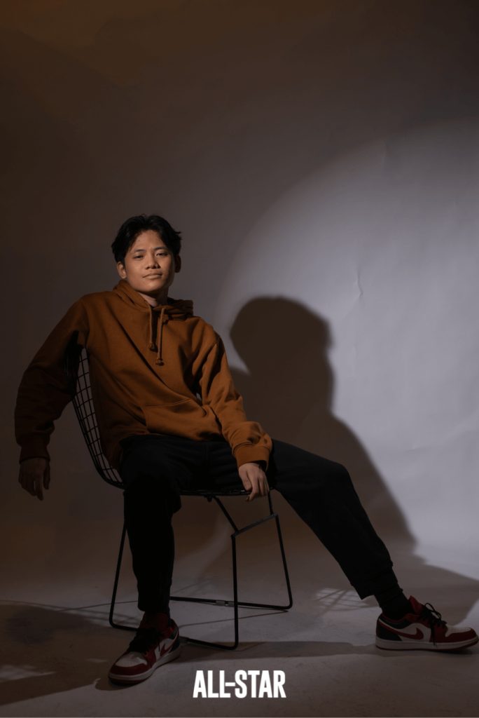 Filipino boy wearing brown hoodie while sitting on a chair